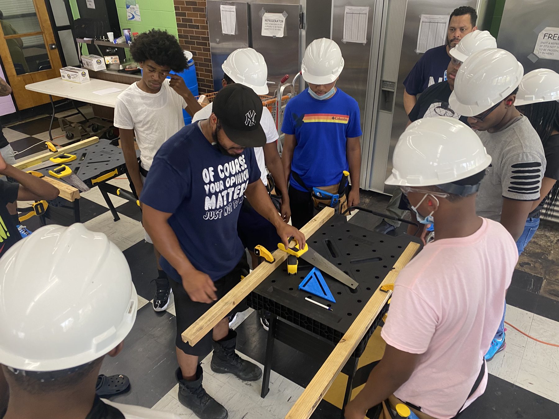 BTW students in hard hats squaring a wood beam during hands-on framing practice